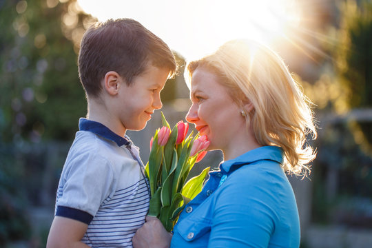 Little boy surprising mom with tulips at Mother's Day