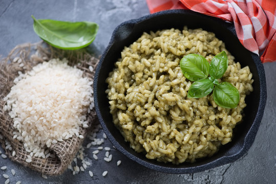 Close-up of spinach risotto in a frying pan and raw rice, high angle view, studio shot