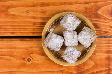 Chocolate cookies with coconut served on the plate over wooden background