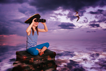 The kid travels on the sea and on the suitcase. © Sergey Khamidulin