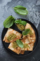 Above view of crepes with basil pesto sauce in a metal plate, vertical shot