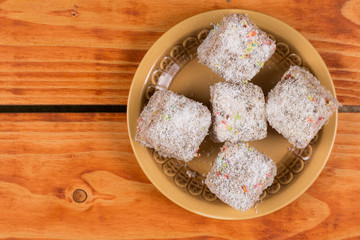 Chocolate cookies with coconut served on the plate over wooden background
