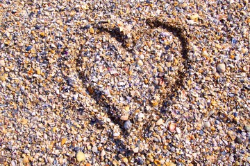 Cuore con conchiglie sulla sabbia