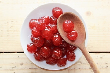 Red cherries on a White plate with a wooden spoon