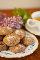 a plate of Molasses cookies with green tea in a vintage porcelain teacup with purple flowers 