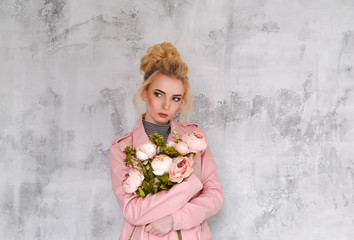 Молодая красивая девушка блондинка позирует в розовой весенней осенней куртке
