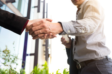 Happy smiling business man shaking hands after a deal finishing up a meeting, business outdoors concept