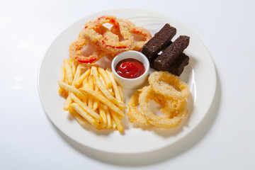Fresh beer snacks assortment on a white plate. French fries, croutons and zucchini and sweet pepper