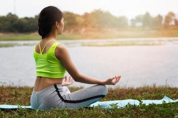 Fototapeta na wymiar Young asian woman in sportswear meditating on yoga mat
