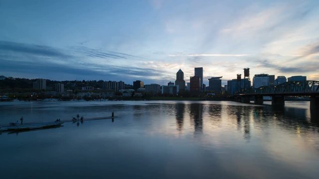 Moving clouds and blue sky over Portland OR downtown city skyline along Willamette River waterfront from sunset into blue hour with water reflection 4k uhd time lapse