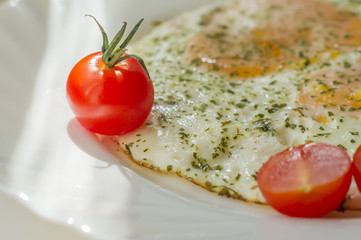 fried eggs on a plate with tomatoes and chopped parsley
