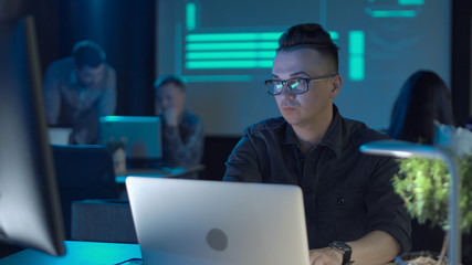 Young male worker programmer or designer sitting at the laptop in modern office.