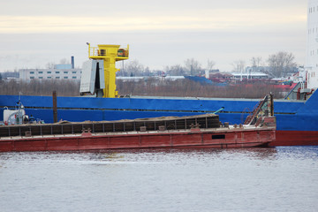 Blue cargo ship and barge with cargo on the river Severnaya Dvina.