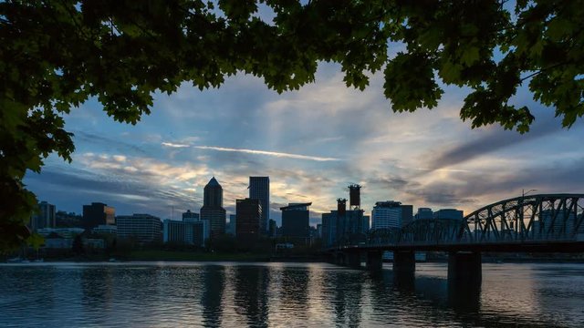 Time lapse 4k uhd video of moving clouds and sky over Portland OR downtown city skyline along Willamette River at sunset into blue hour at dusk 4096x2304