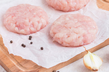 Raw chicken cutlets on parchment paper. Wooden background. Uncooked turckey burgers on wooden board. Preparing dinner.