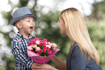 Small son gives his beloved mother a beautiful bouquet of pink roses . Spring, concept of family...