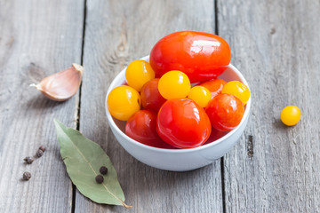 Colorful cherry tomatoes in a white ceramic plate. Salty tomatoes. Fermented vegetables. Red and yellow cherry tomatoes.