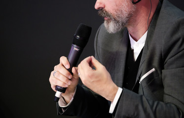 Businessman talking at conference holding a microphone
