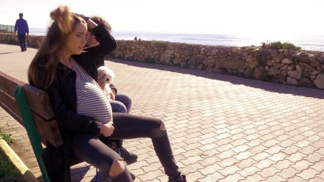 Pregnant woman starting to feel pain having contractions sitting on bench with boyfriend