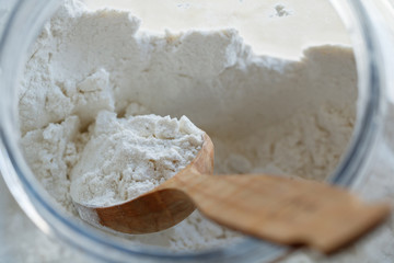 Close-up of a spoon with flour inside a large container