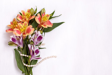 a small bouquet of alstromeria with a pearl thread on white background