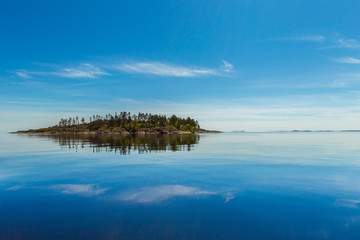 Reflection in the water of clouds. Island on the surface of the water.
