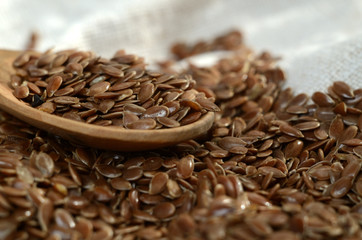 Close up flax seeds in the wooden spoon on a linen textile