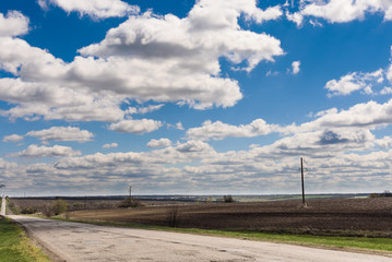 Clouds on a blue sky, road and field