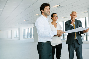 Estate broker and clients discussing over blueprint of new offic