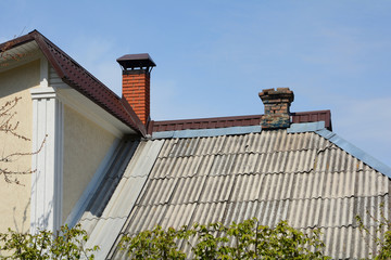 The roof is of asbestos roof slate. Old house attached to the new house. Old roof slates and chimney.