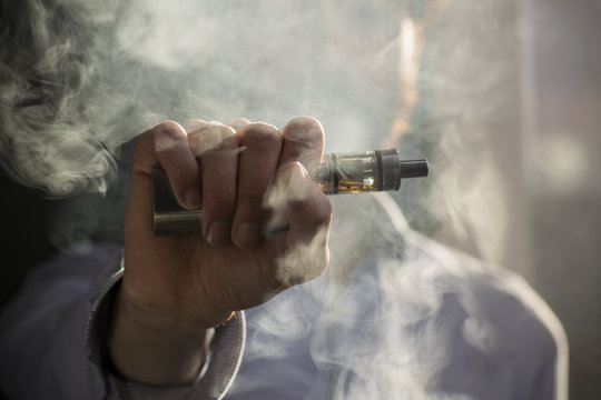 man vaping electronic cigarette with clouds.