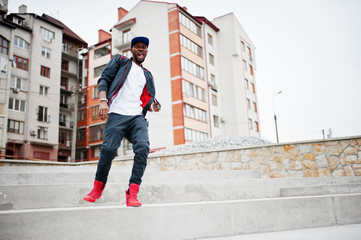 Portrait of jumping stylish african american man on sportswear, cap and glasses. Black men emotion model street fashion.