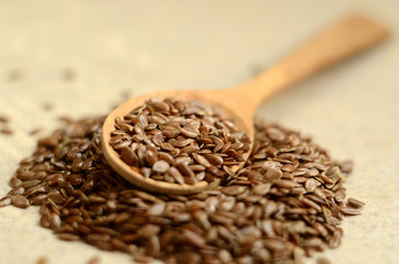 Close up flax seeds in the wooden spoon on a linen textile