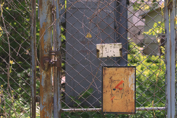 Danger. Fence from the grid overgrown with branches. There is a lock on the door.