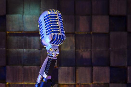 Retro microphone on wood brown background in sound recording room. On air concept. Music background with copy space