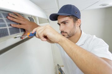 portrait of mid-adult male technician repairing air conditioner