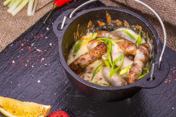 Sausages from beef with cheese sauce, are served with vegetables and greens