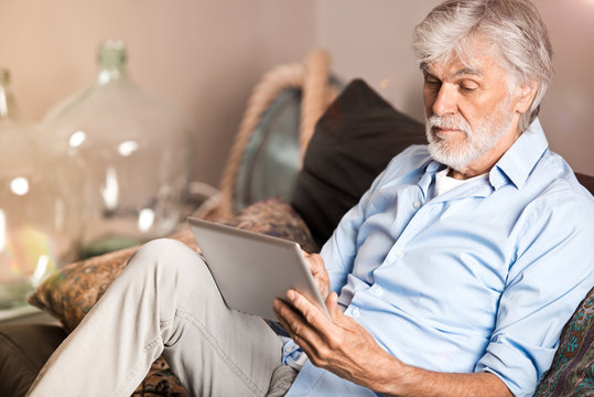 Senior mit Tablet-Computer im Wohnzimmer