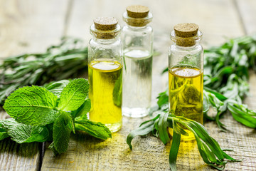 natural cosmetic oil with fresh rosemary and mint on light wooden table background