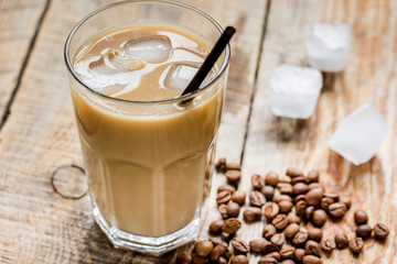 cold coffee glass with ice cubes on wooden table background