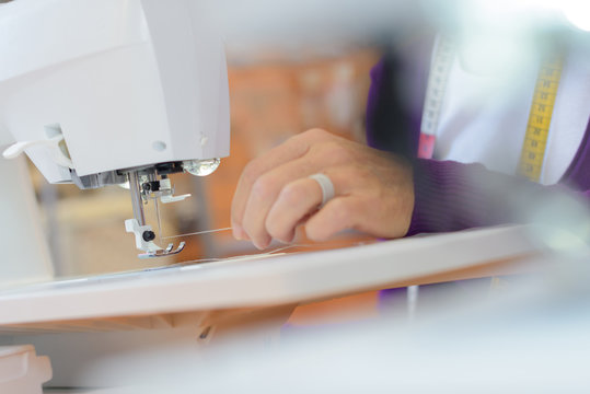 Closeup of woman threading needle on sewing machine