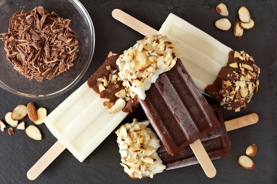 Chocolate and almond ice pops in a cluster, overhead scene over a slate background