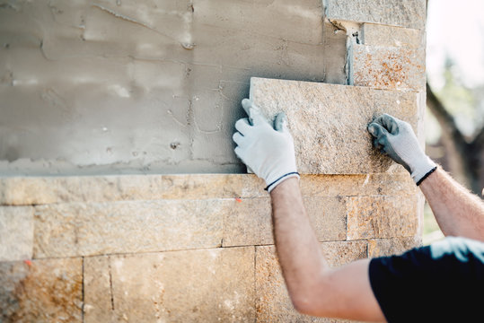 Construction Worker Installing Stone On Architectural Facade Of New Building. Details Of Construction Industry