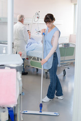 Woman sweeping floor in hospital room