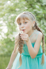 Little beautiful girl playing outdoors in park, blowing on dandelion