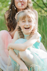 Family from mother and daughter playing outdoors. Sitting on green grass, smiling