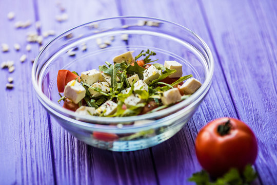 Tasty fresh salad and tomate on purple wooden table. Food