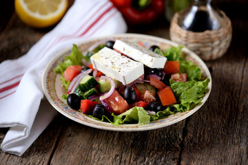 Classic Greek salad from tomatoes, cucumbers, red pepper, onion with olives, oregano and feta cheese.