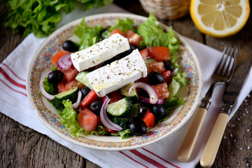 Classic Greek salad from tomatoes, cucumbers, red pepper, onion with olives, oregano and feta cheese.