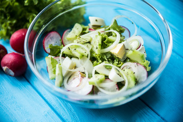 Fresh salad of cucumbers, radishes and herbs on wooden table. Top view